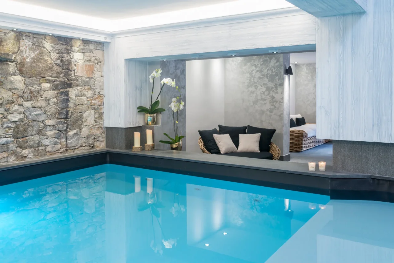 Piscine intérieure du spa de l’Hôtel La Chaudanne, bordée d’un mur en pierre et d’un espace de repos.