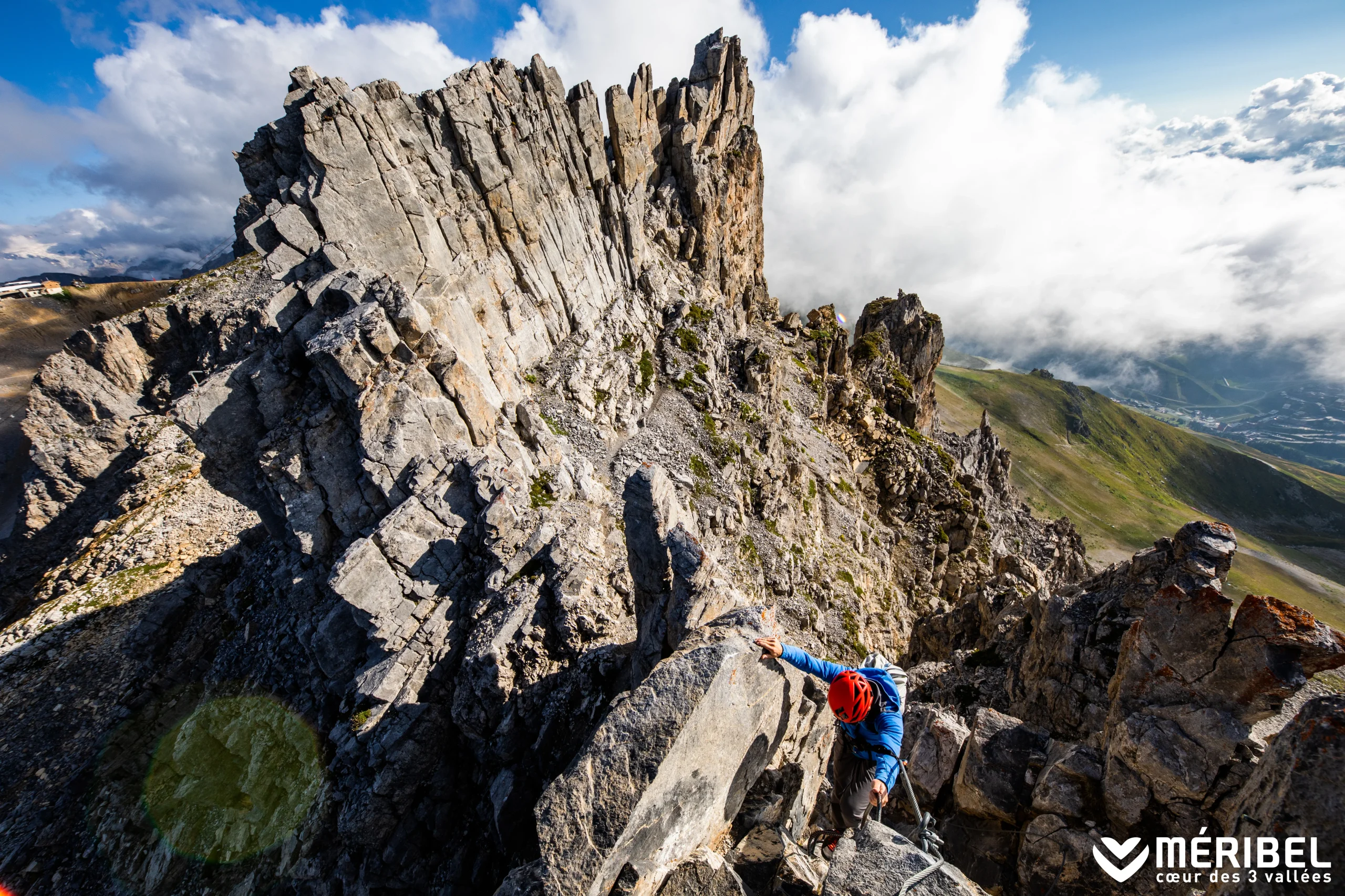 Personne casquée progressant sur une arête rocheuse équipée d’un câble à Méribel.