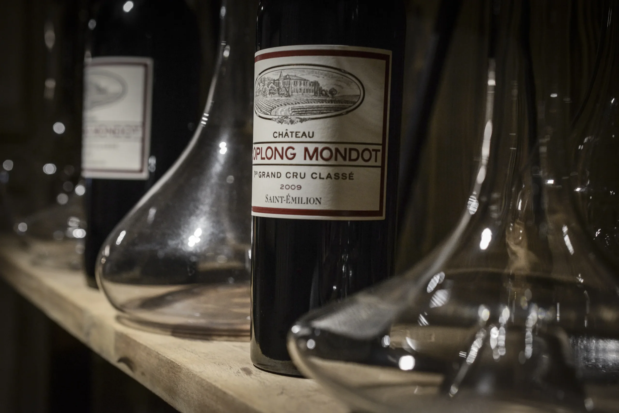 Bouteille de Château Troplong Mondot 2009, Saint-Émilion, entre des carafes à décanter sur une étagère.