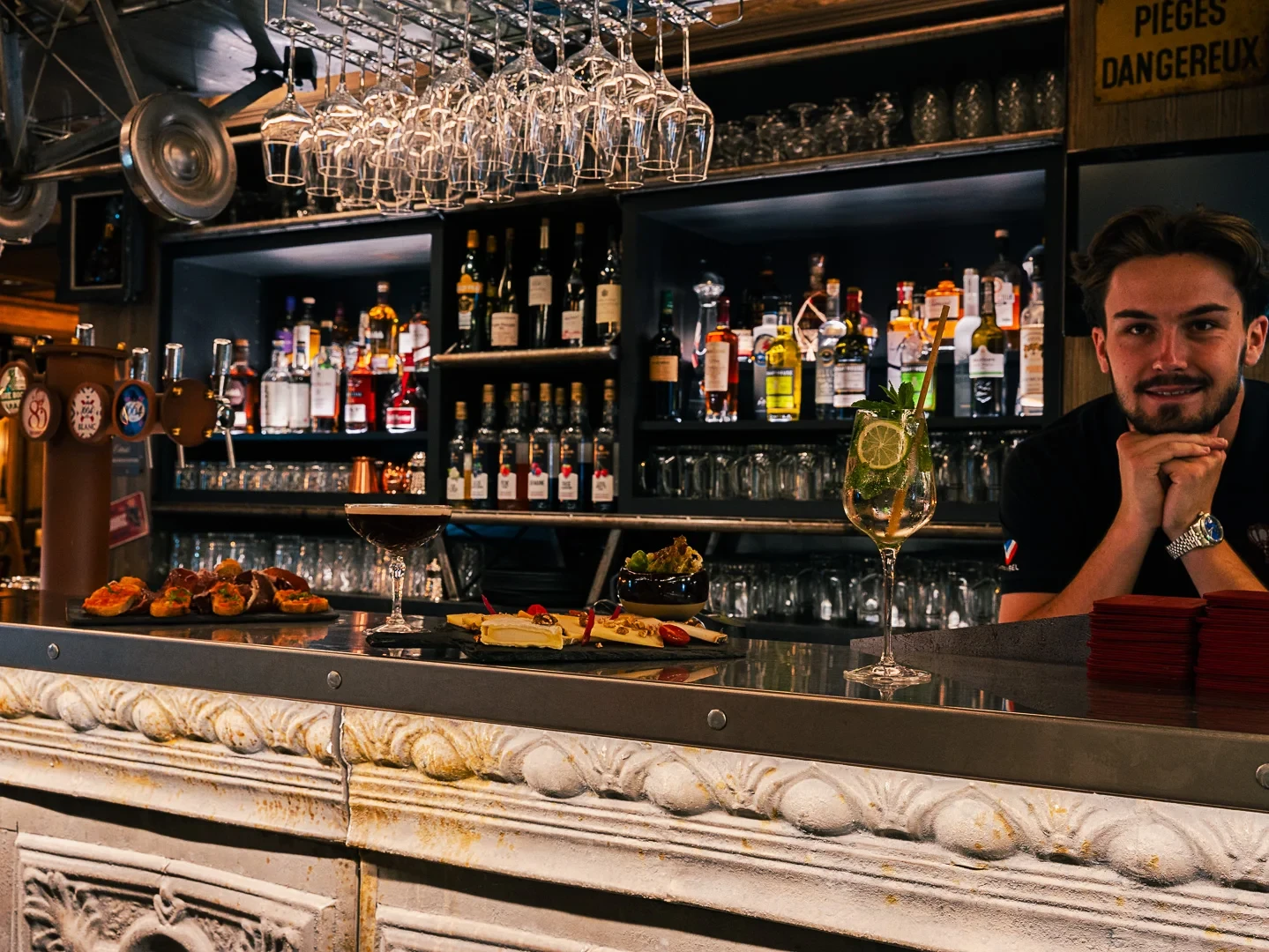 Un barman derrière un comptoir garni de cocktails et de bouchées apéritives.