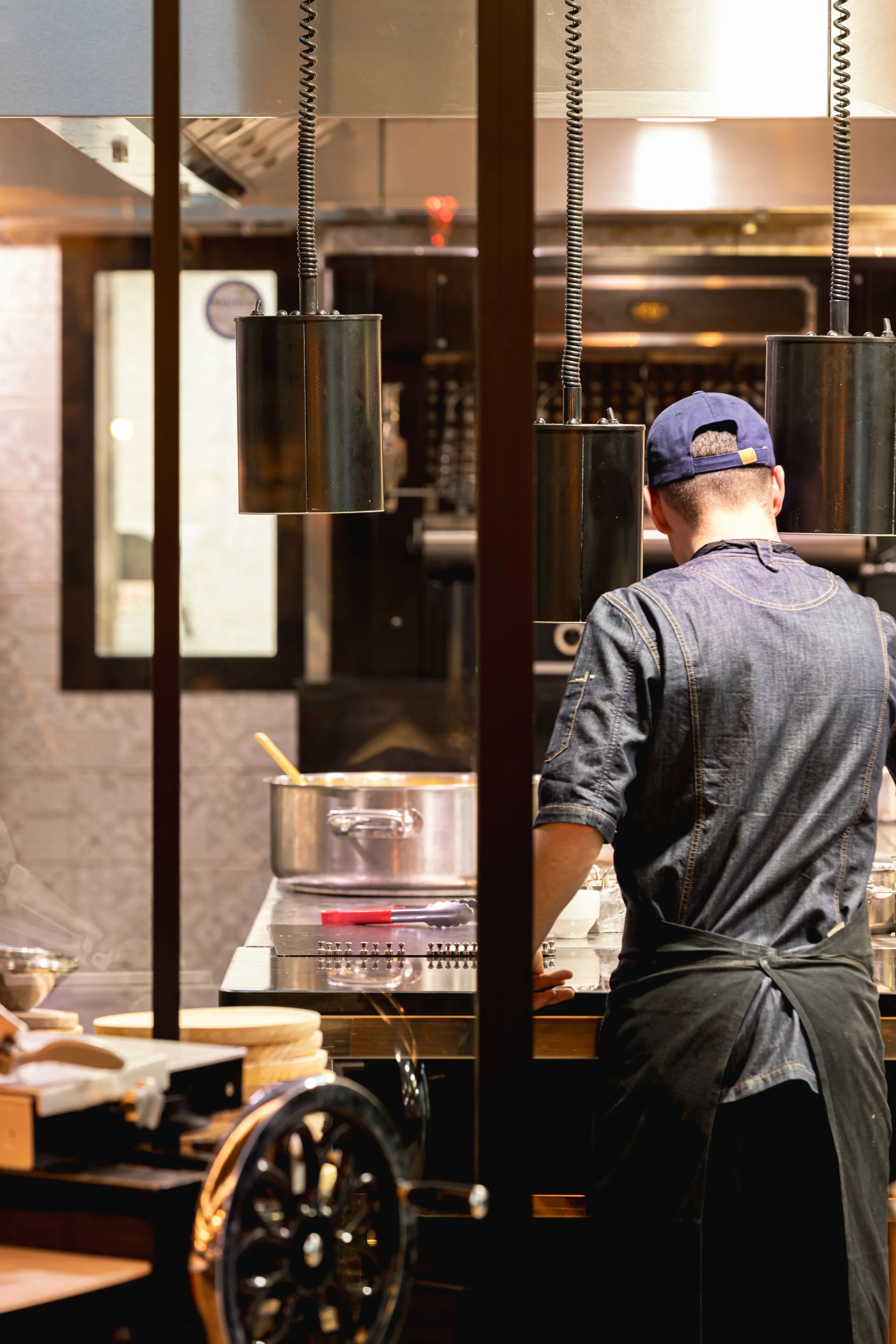 Un cuisinier de dos à son poste de travail dans les cuisines de l’Hôtel La Chaudanne.