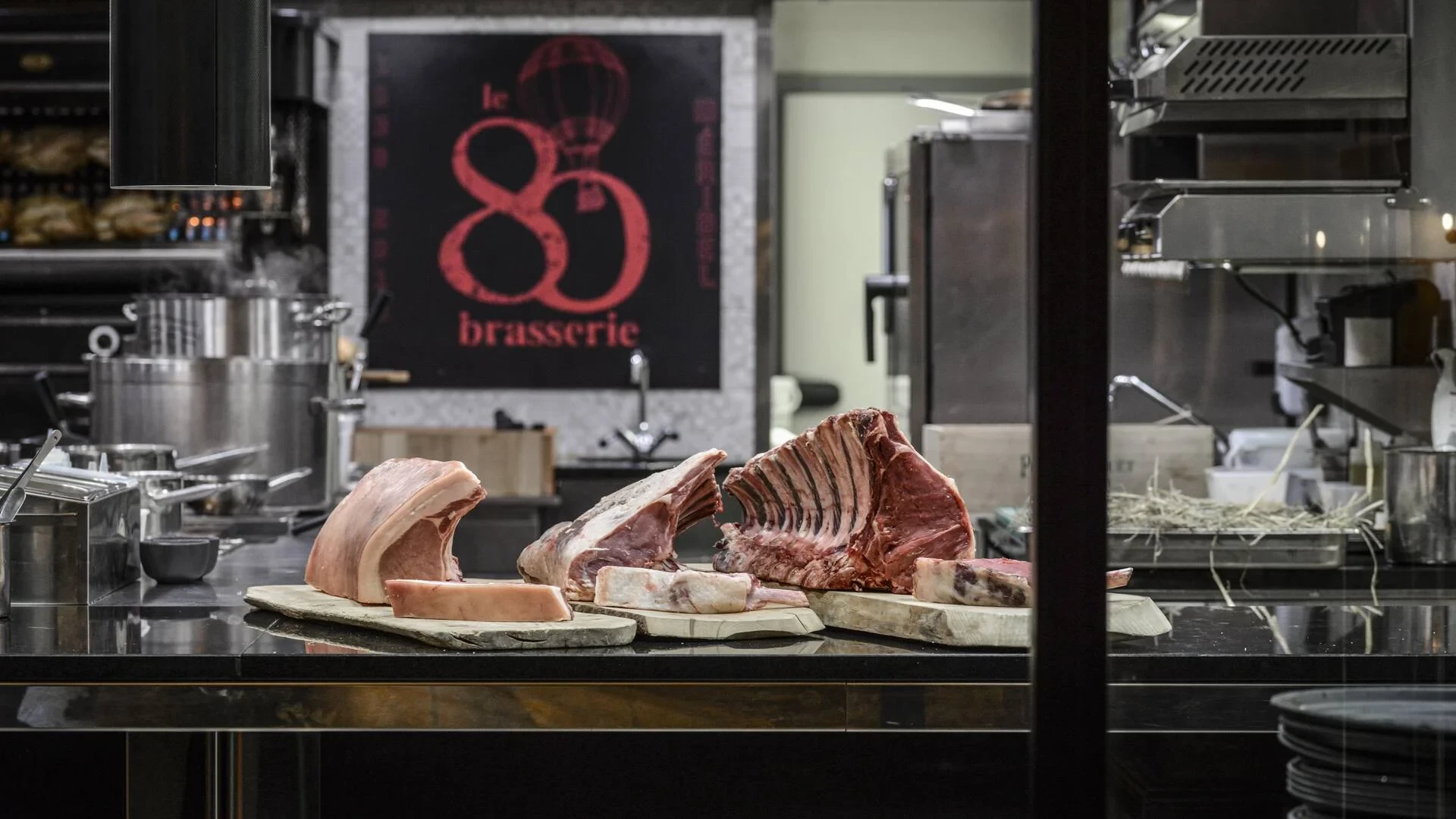 Pièces de viande crue avec côtes disposées sur des planches dans la cuisine de la brasserie Le 80.