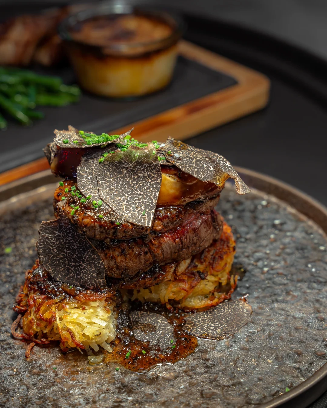 Pièce de bœuf sur des galettes de pommes de terre dorées, surmontée de foie gras et de fines lamelles de truffe.