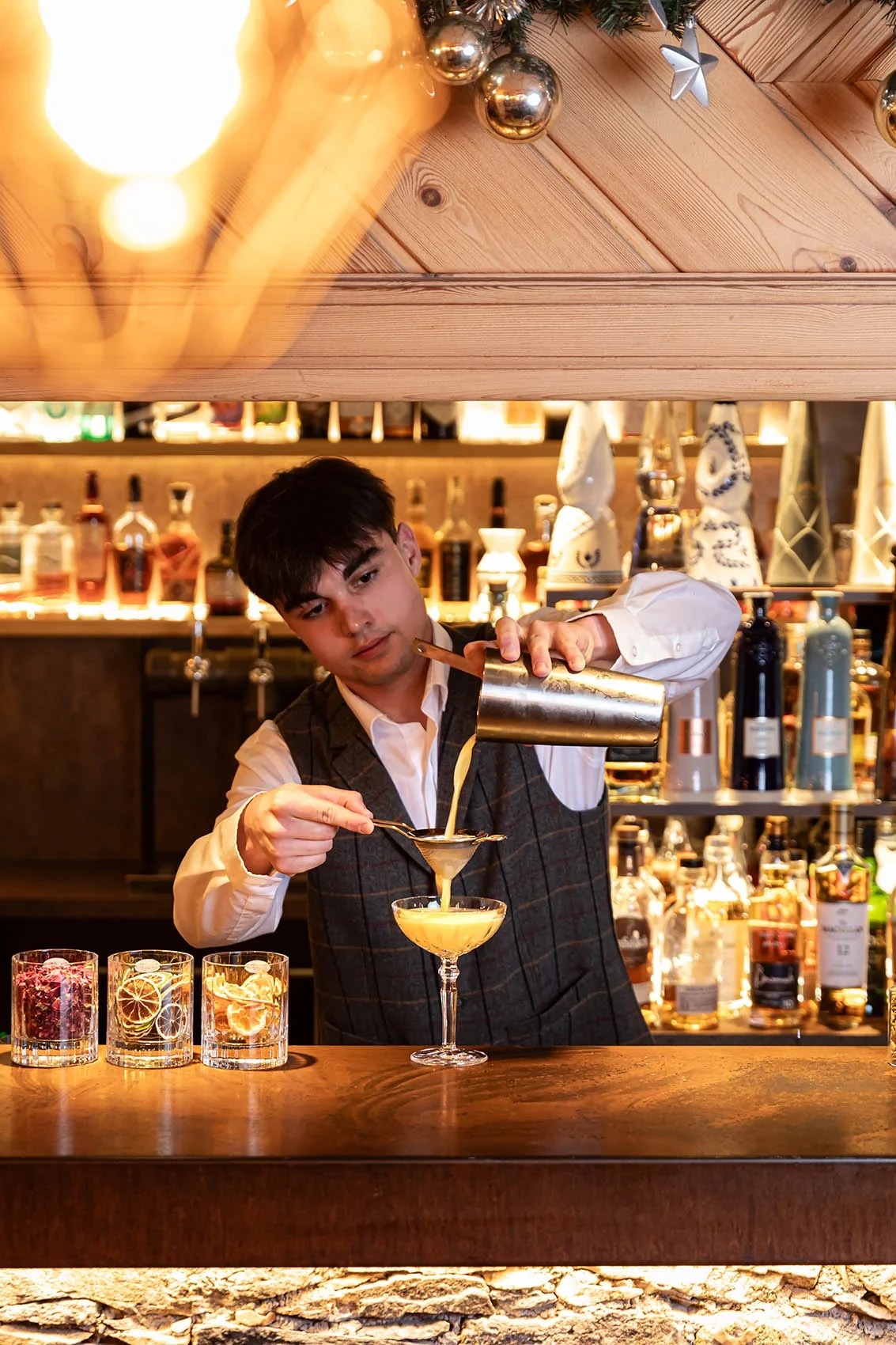 Un barman filtre un cocktail dans une coupe au bar de l’Hôtel La Chaudanne.