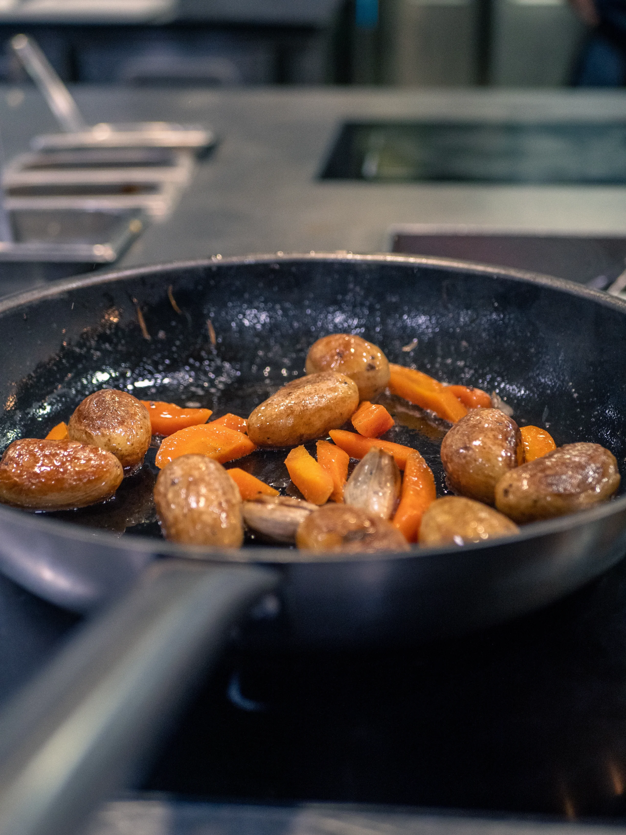 Pommes de terre dorées, carottes et échalotes dans une poêle.
