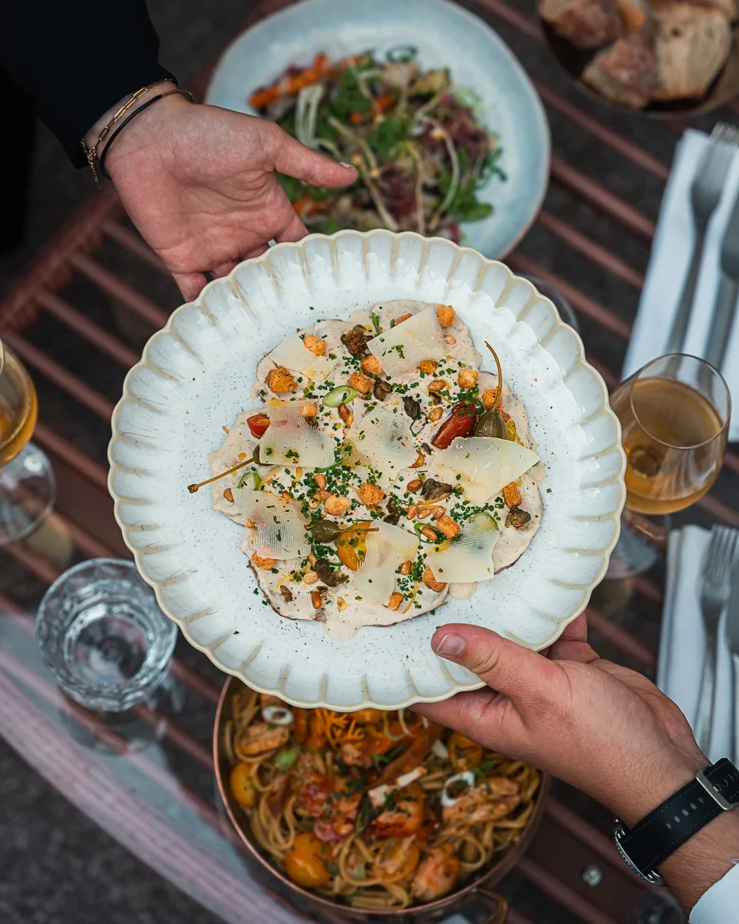 Grande assiette de fines tranches nappées de sauce, garnies de copeaux de fromage, de câpres et de croûtons.