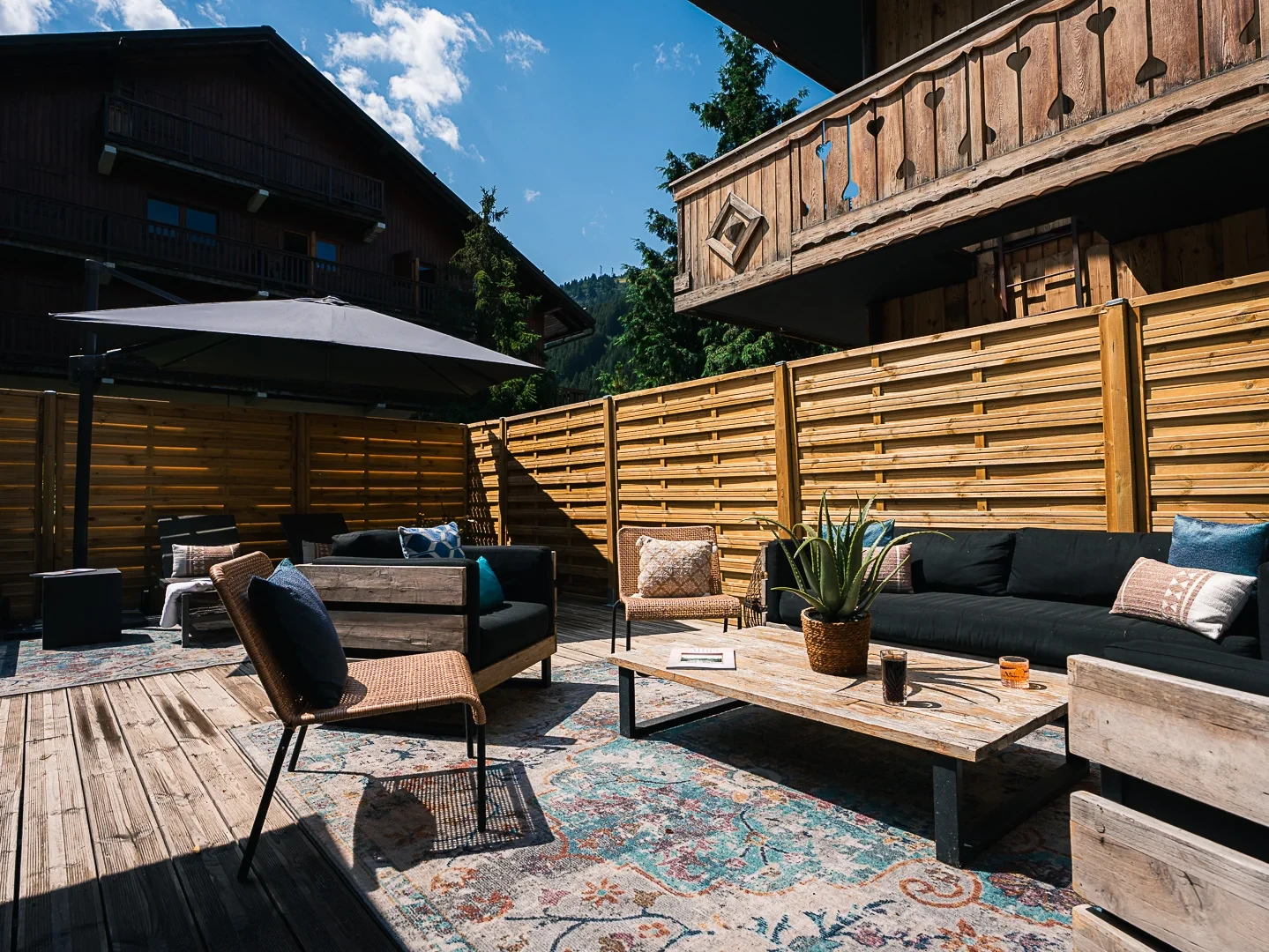 Terrasse du spa Nuxe de l’Hôtel La Chaudanne à Méribel, avec canapés, fauteuils et tables basses entre les chalets en bois.