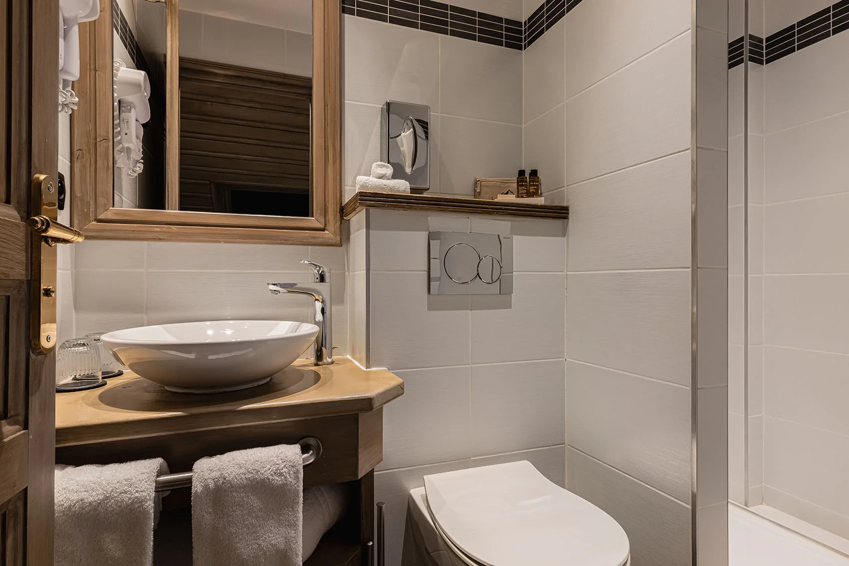 Salle de bains de l’Hôtel La Chaudanne, hôtel 4 étoiles à Méribel, avec vasque sur meuble en bois et douche vitrée.