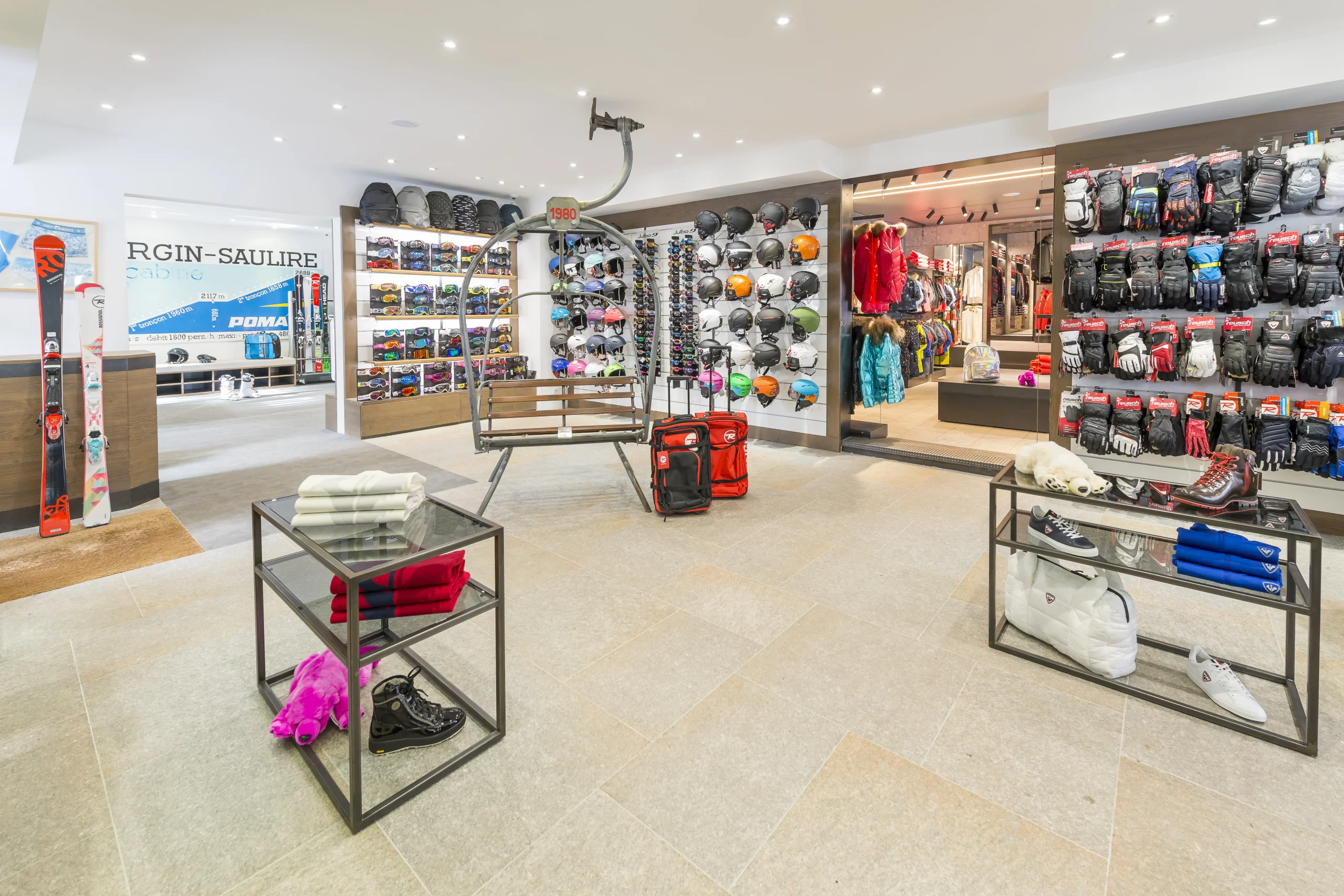 Espace ski shop de l’Hôtel La Chaudanne, avec casques, masques et gants de ski autour d’un siège de télésiège exposé.