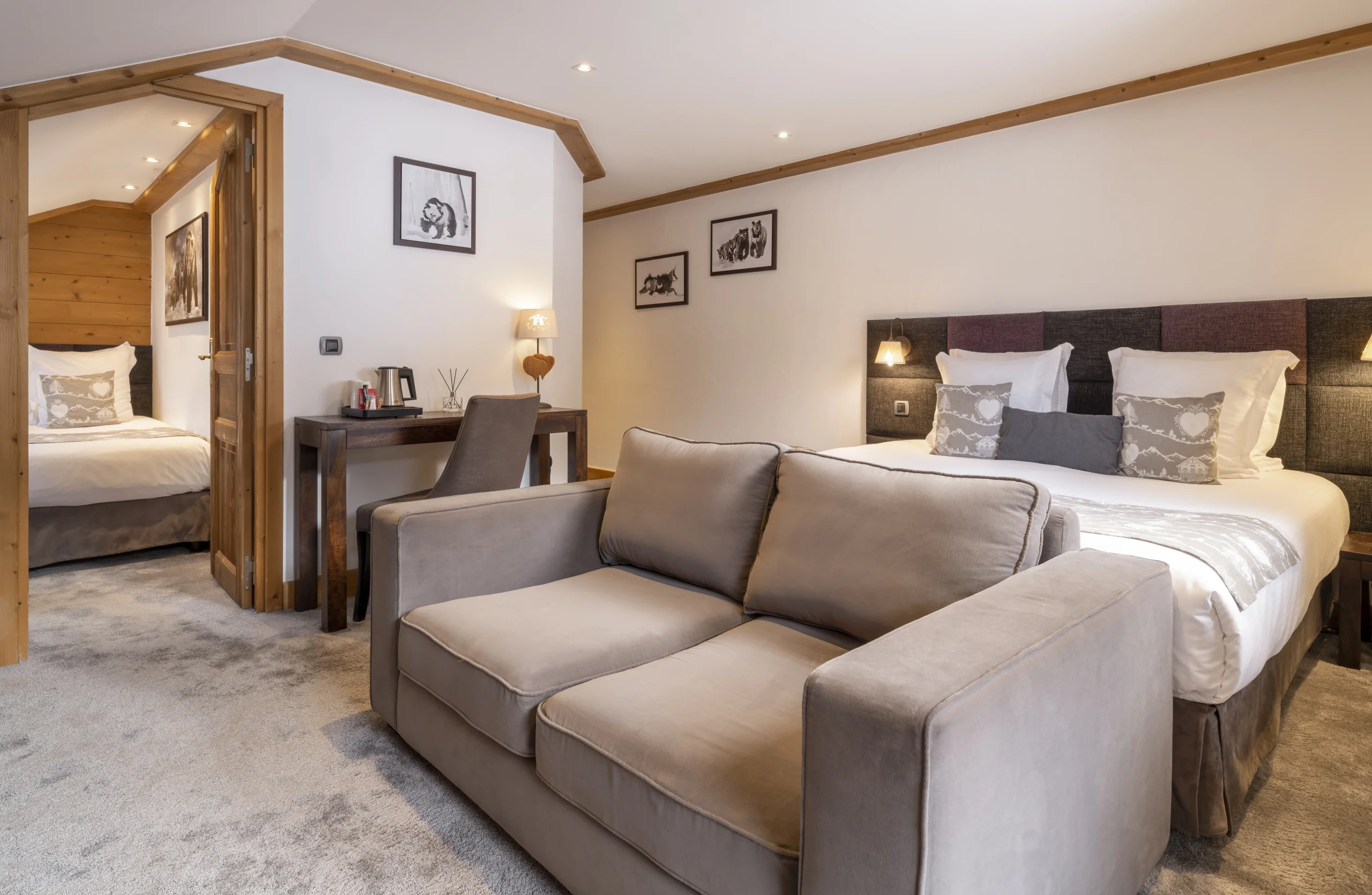 Chambre de l’Hôtel La Chaudanne, hôtel 4 étoiles à Méribel, avec lit double, canapé et ouverture sur un second espace nuit.