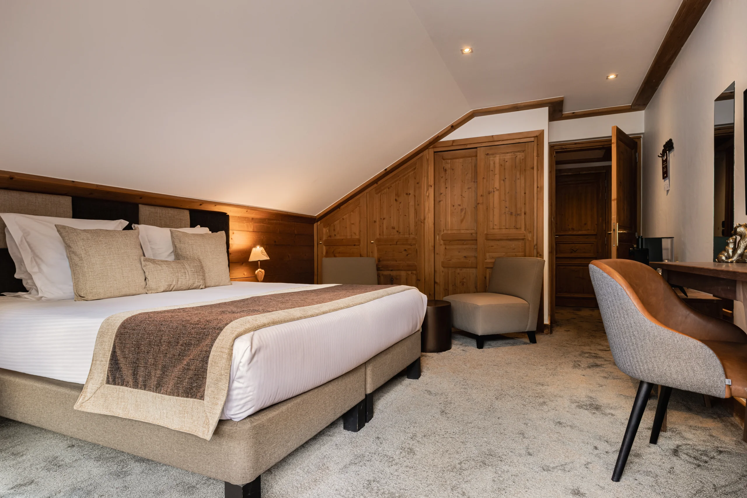 Chambre mansardée de l’Hôtel La Chaudanne, hôtel 4 étoiles à Méribel, avec lit double et placards en bois.