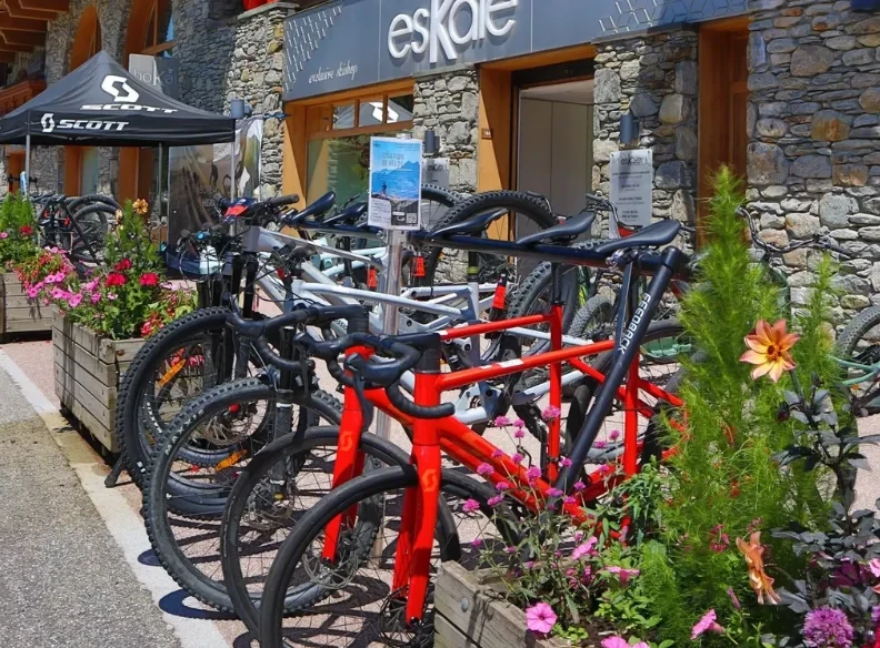 Vélos exposés devant la façade en pierre de l’Eskale, boutique de l’Hôtel La Chaudanne proposant la location de VTT à Méribel.