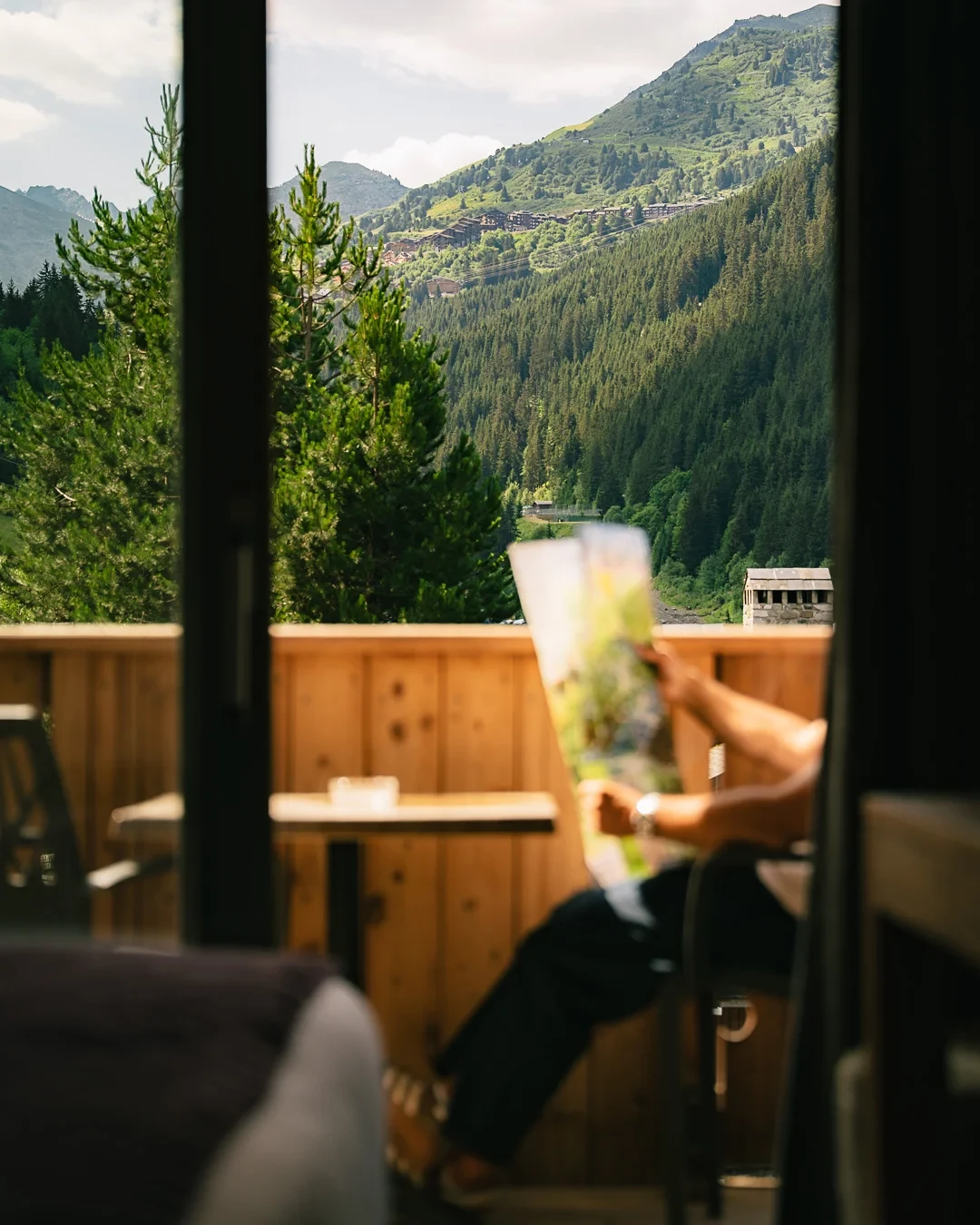 Balcon d’une chambre de l’Hôtel La Chaudanne, hôtel 4 étoiles à Méribel, avec vue sur les montagnes boisées.