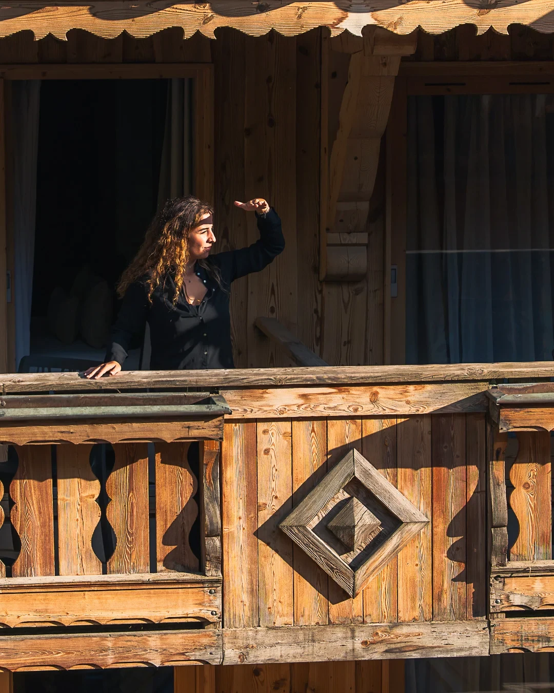 Femme sur un balcon en bois ensoleillé de l’Hôtel La Chaudanne, hôtel 4 étoiles à Méribel.