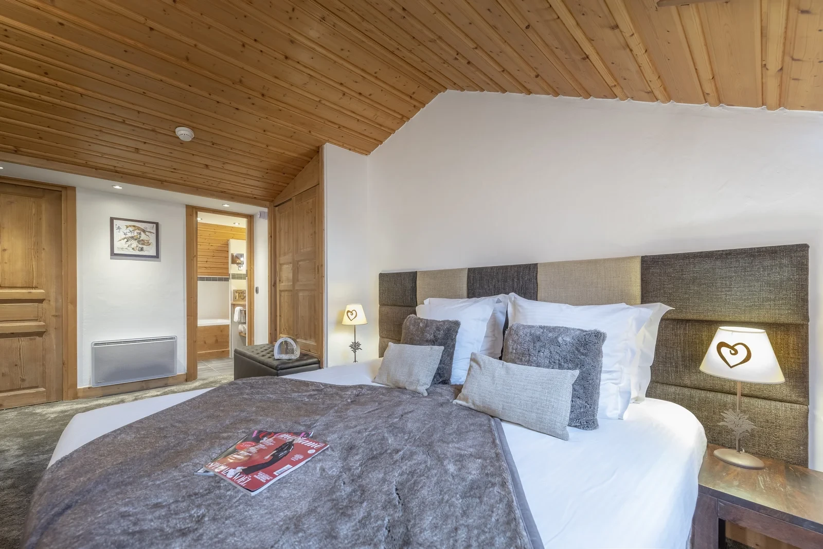 Lit double à tête de lit capitonnée sous un plafond en bois à l’Hôtel La Chaudanne, hôtel 4 étoiles à Méribel.