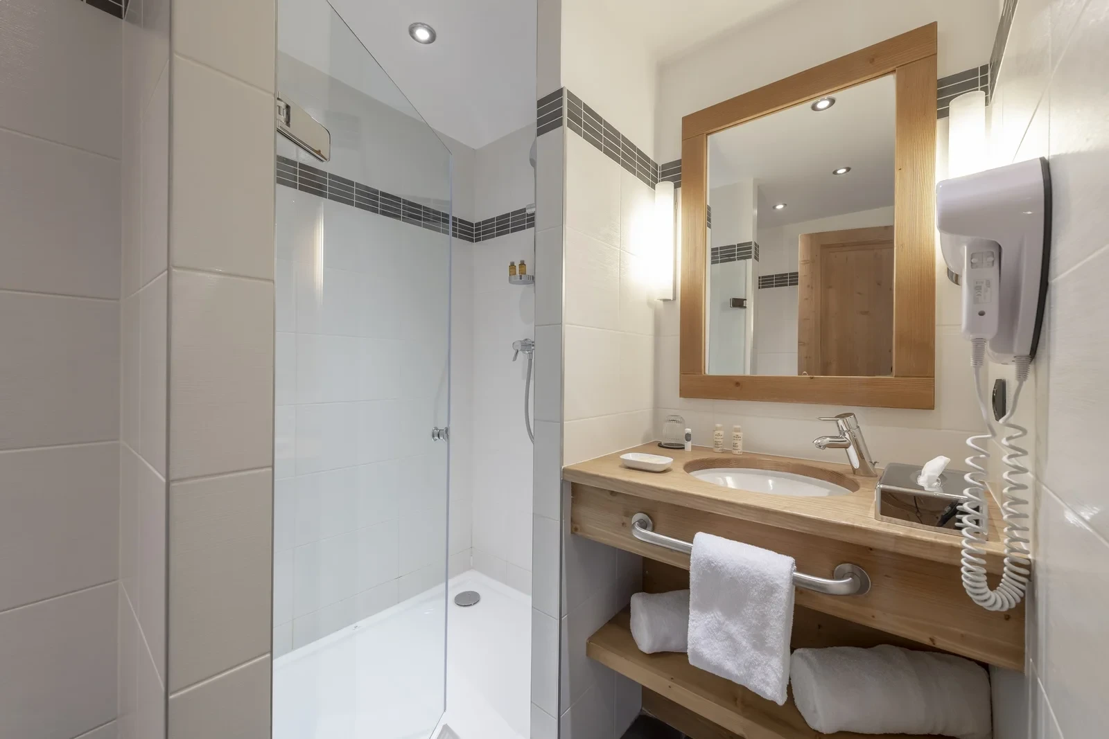 Salle de bain de l’Hôtel La Chaudanne avec douche vitrée et vasque encastrée dans un meuble en bois.