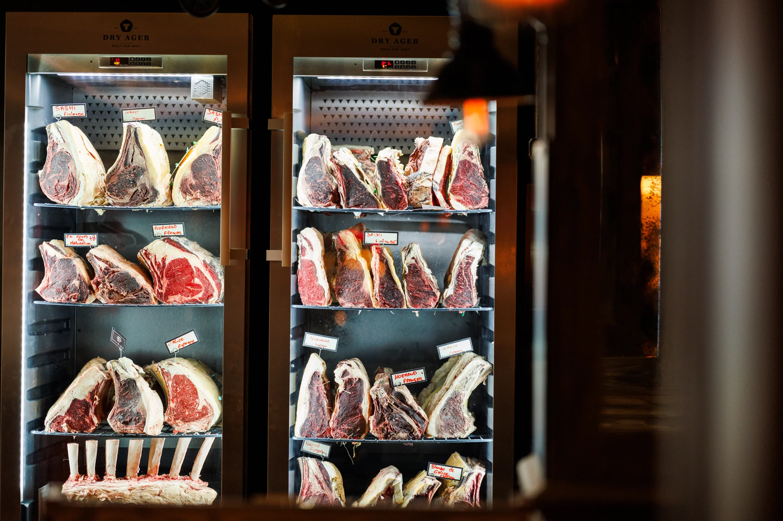 Pièces de bœuf disposées sur les étagères de deux armoires vitrées de maturation.