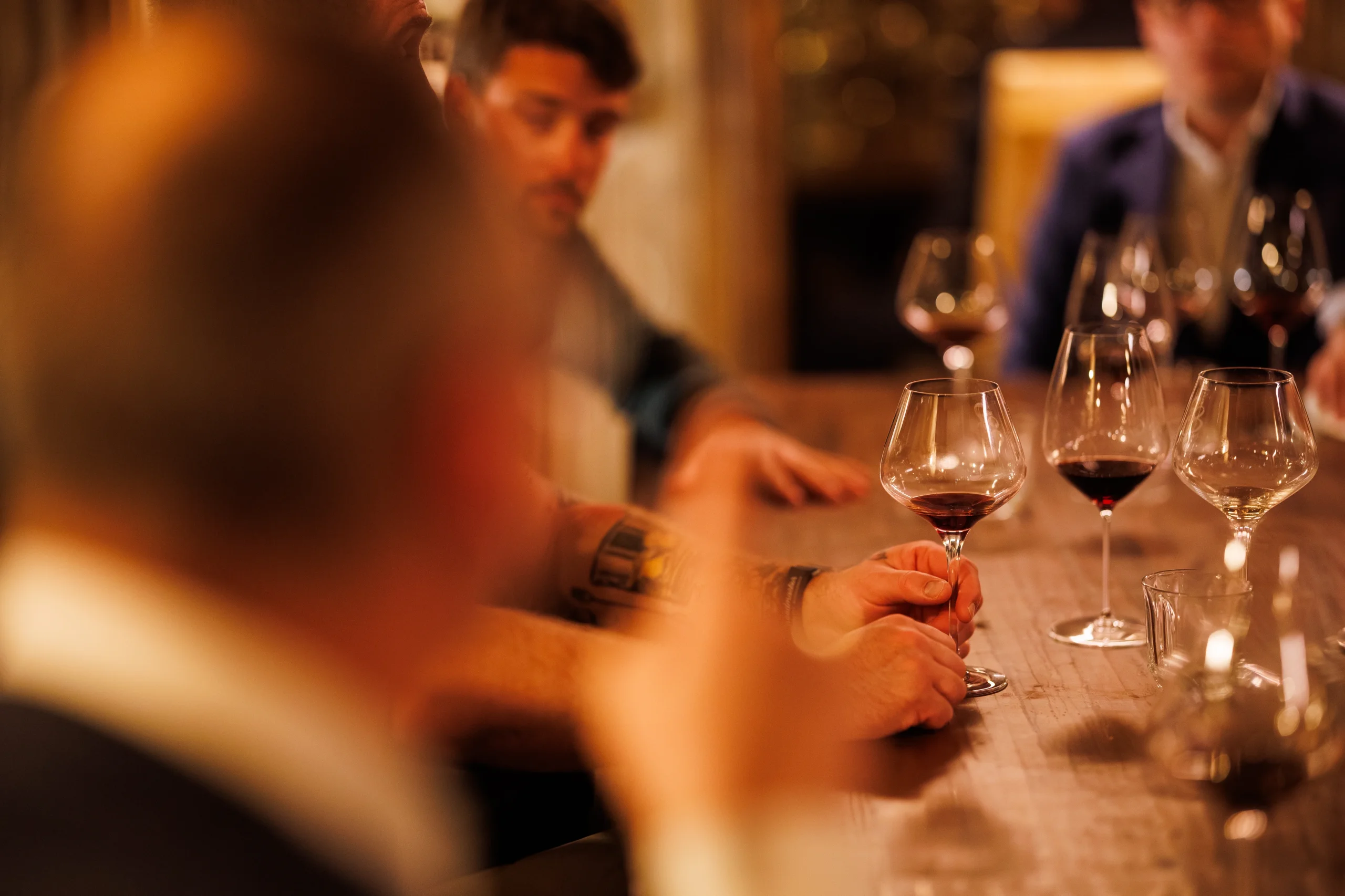 Des participants réunis autour d’une table pour une dégustation de vin rouge.