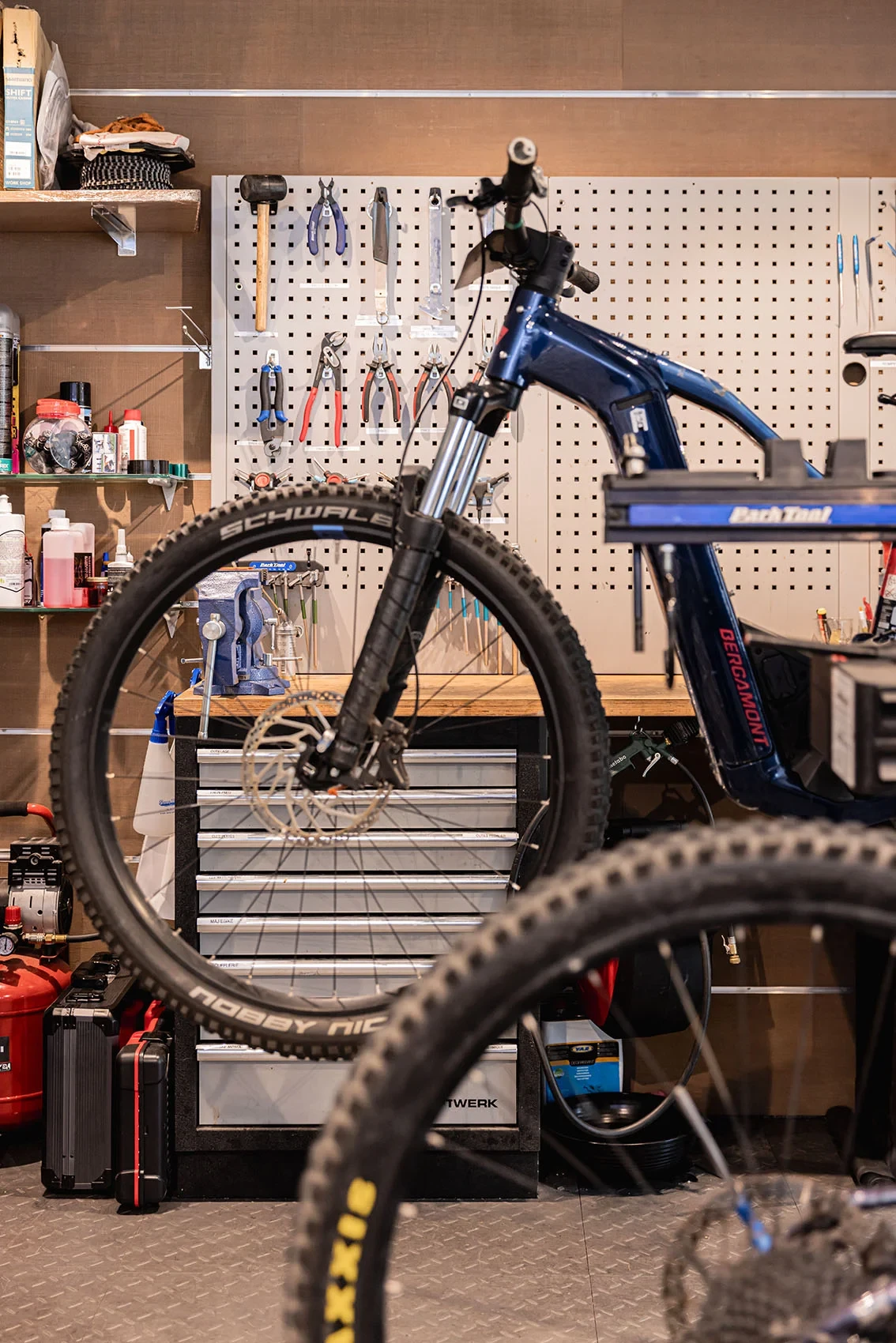 VTT fixé sur un pied d’atelier devant un établi et un panneau d’outils.