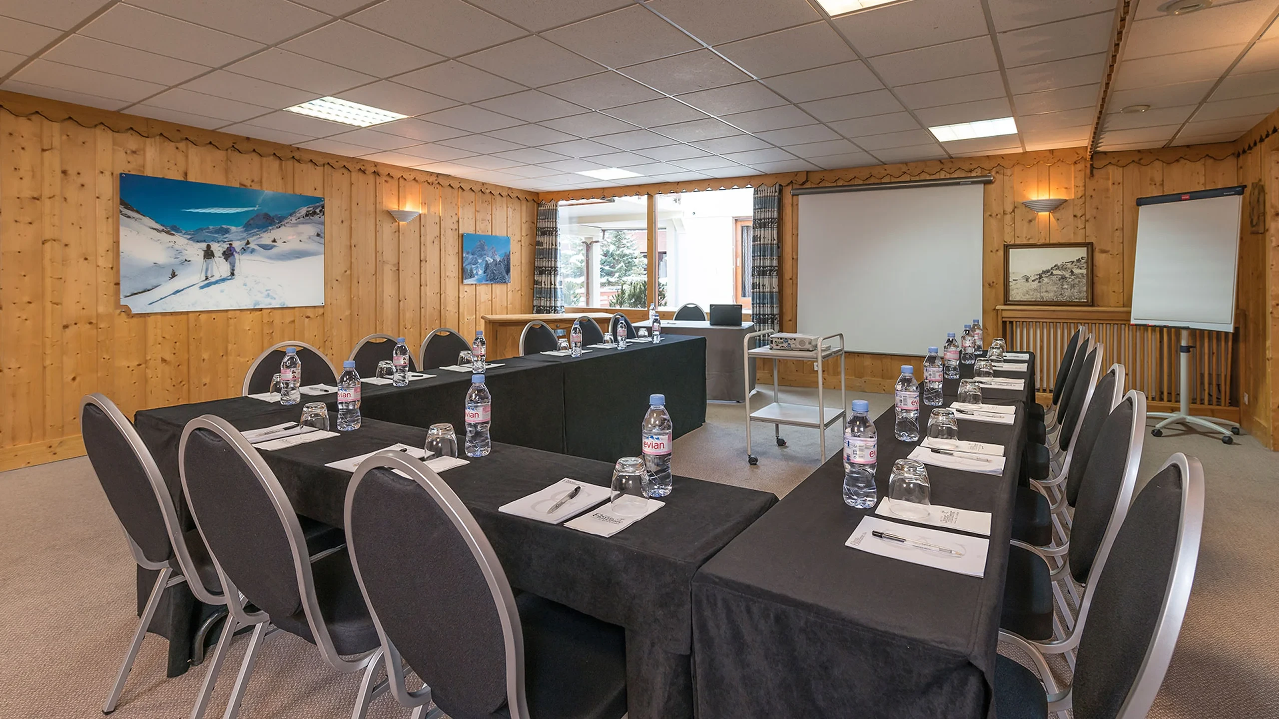 Salle de séminaire à Méribel de l’Hôtel La Chaudanne, avec tables disposées en U, écran de projection et paperboard.