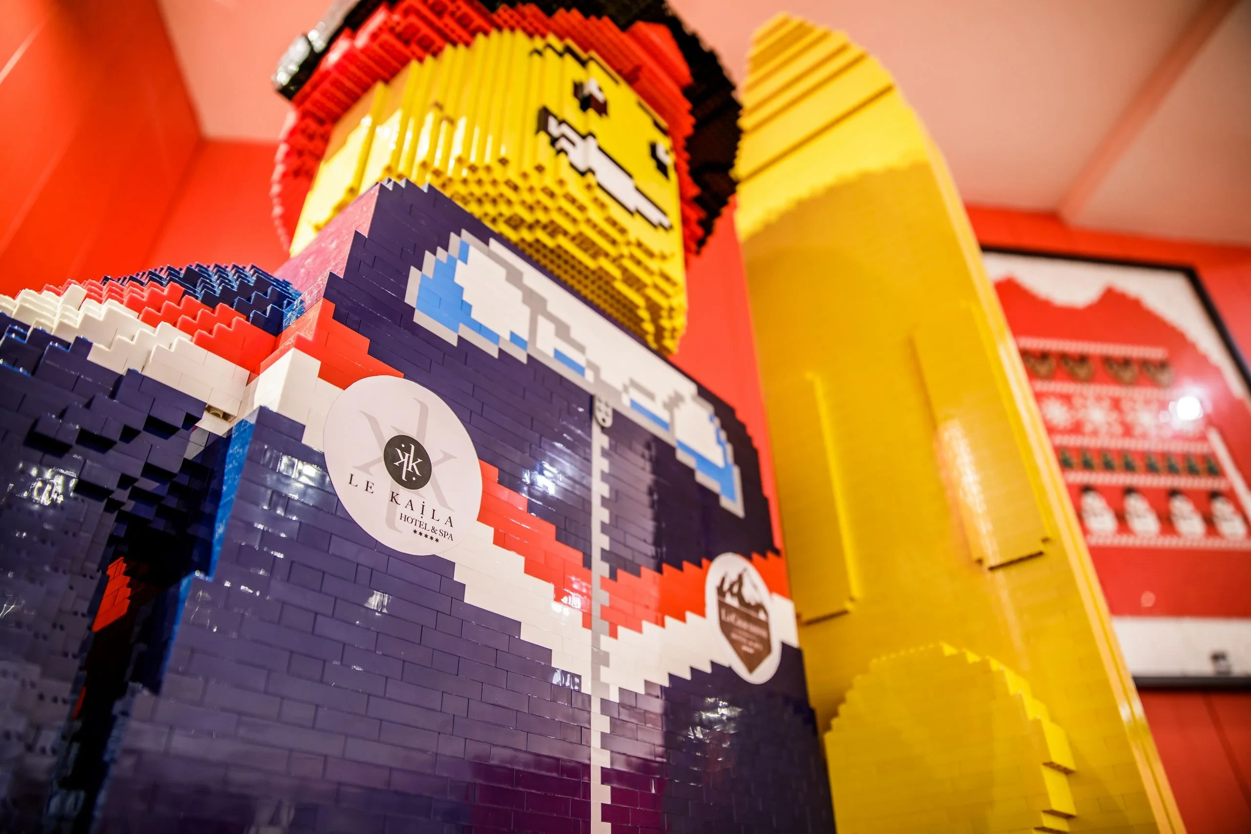 Grand personnage de skieur en briques LEGO, avec lunettes sur le front et ski jaune à ses côtés.