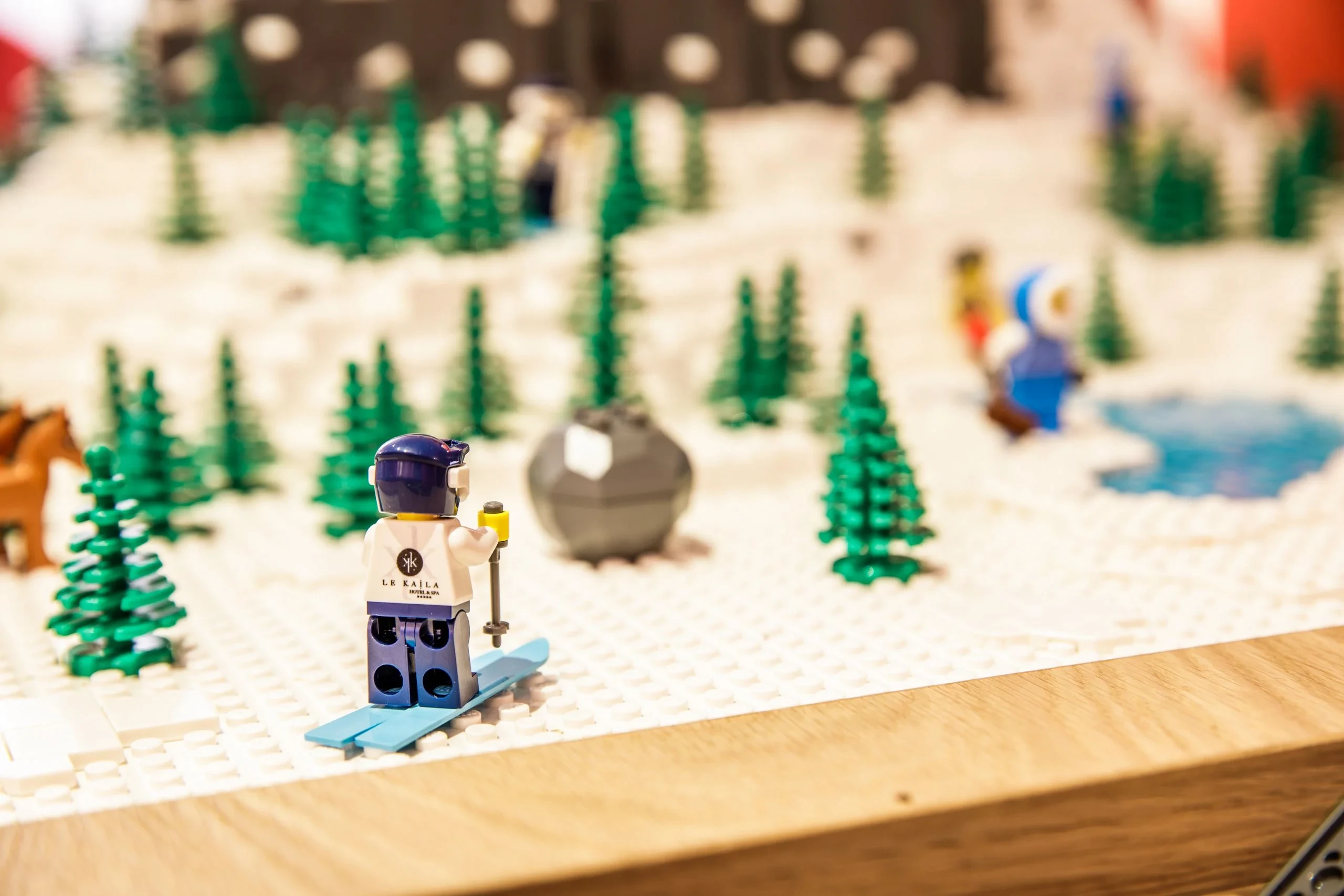 Figurine LEGO chaussée de skis bleus dans une maquette enneigée parsemée de sapins.