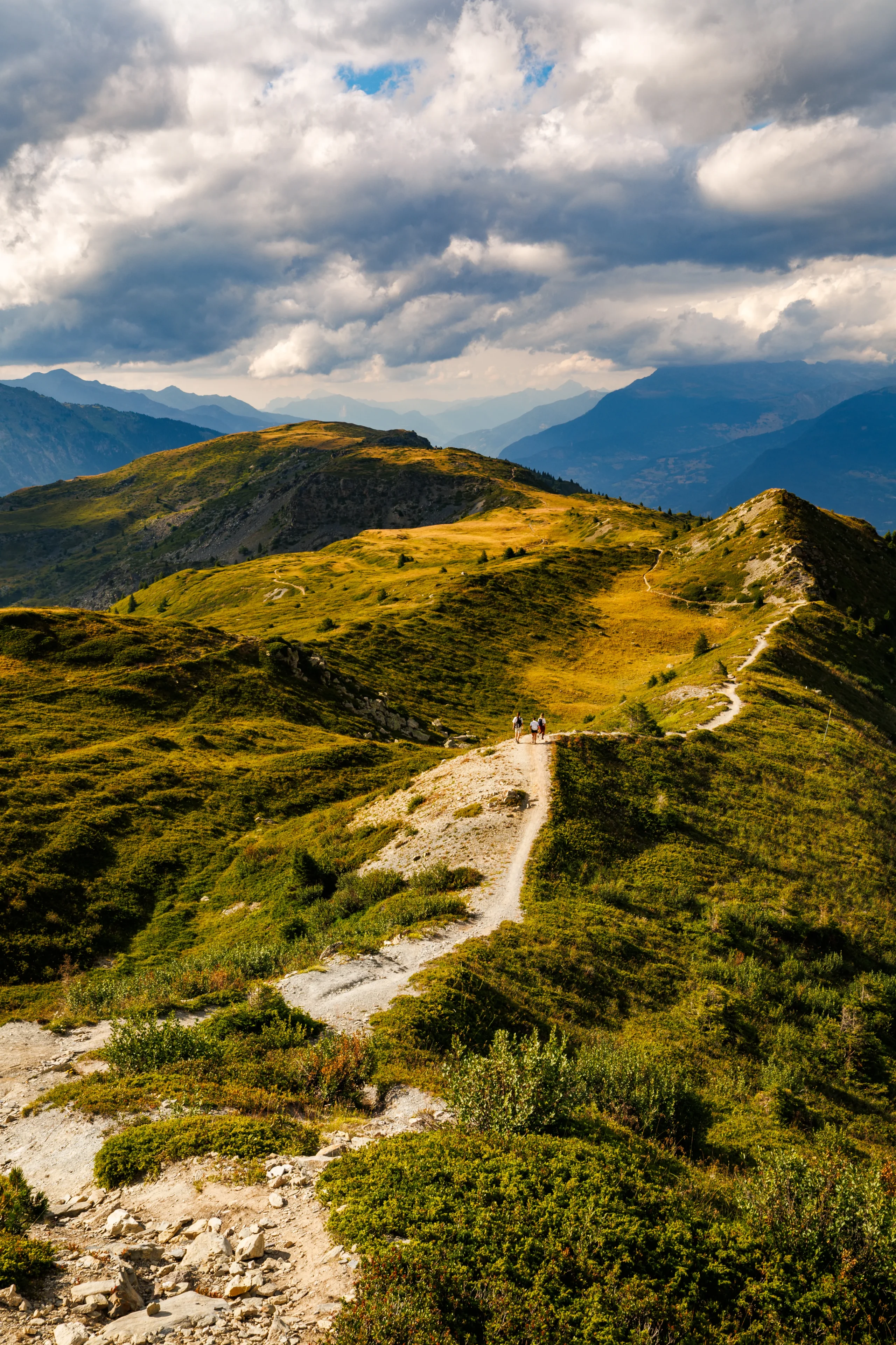 Randonnée à Méribel sur un sentier de crête traversant les alpages, avec trois marcheurs face aux montagnes.