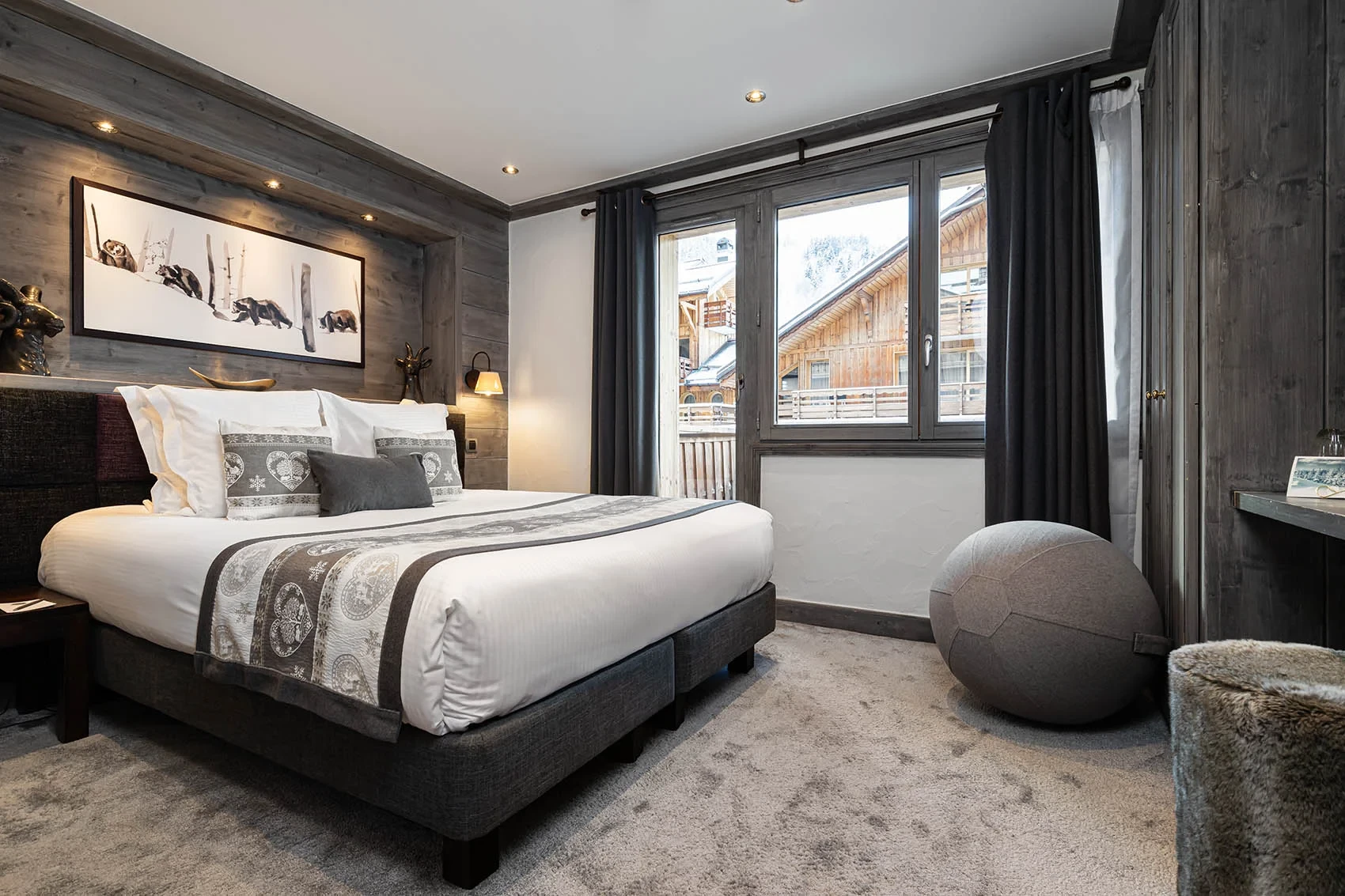 Chambre de l’Hôtel La Chaudanne, hôtel 4 étoiles à Méribel, avec lit double et boiseries grises.