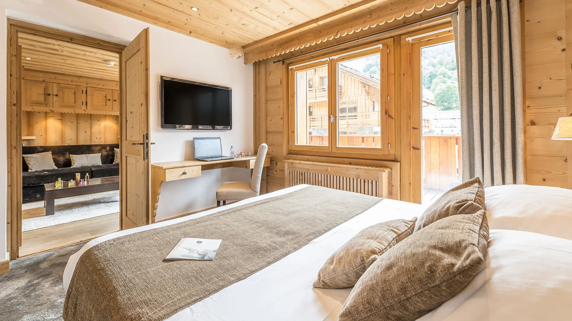 Chambre de l’Hôtel La Chaudanne, hôtel 4 étoiles à Méribel, avec lit double, habillage en bois et accès au balcon.